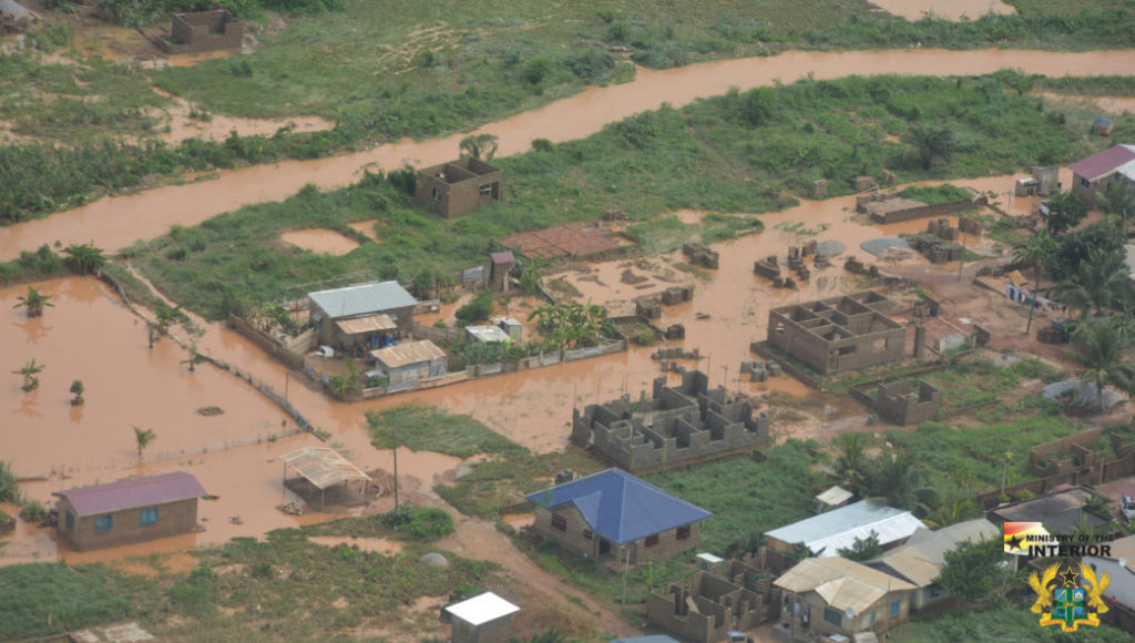 Aerial view of flood damage in rural Ghana community showing homes surrounded by muddy floodwater