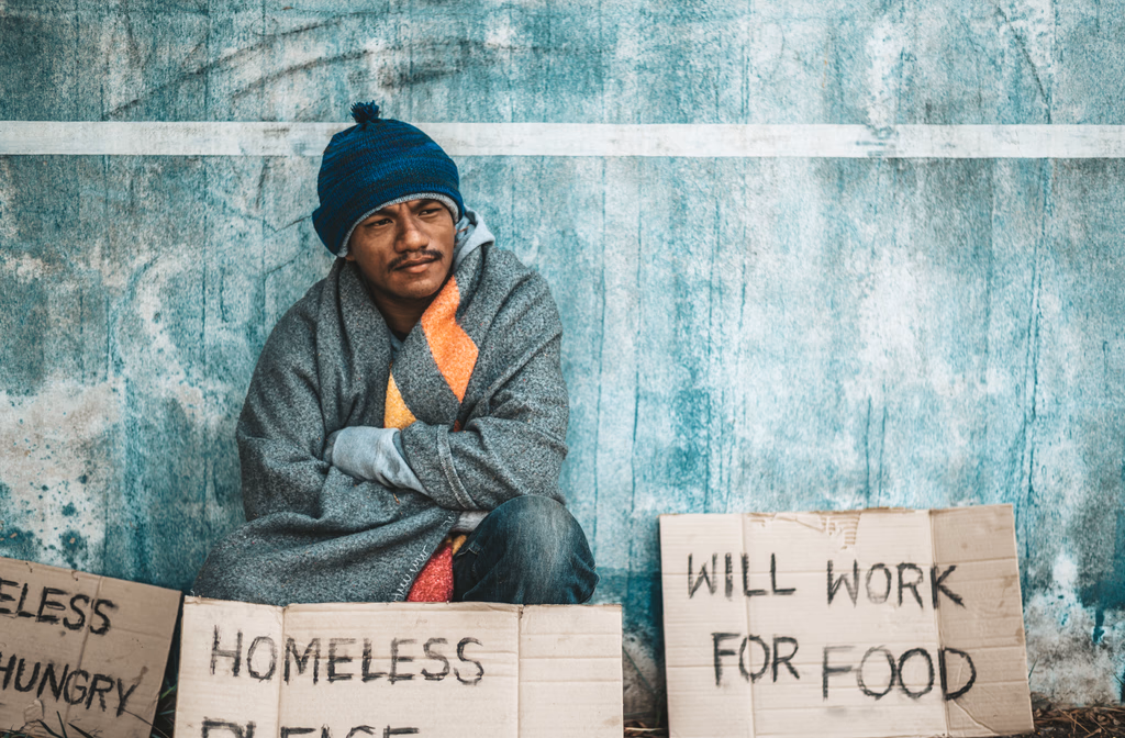 Person experiencing homelessness with sign asking for help